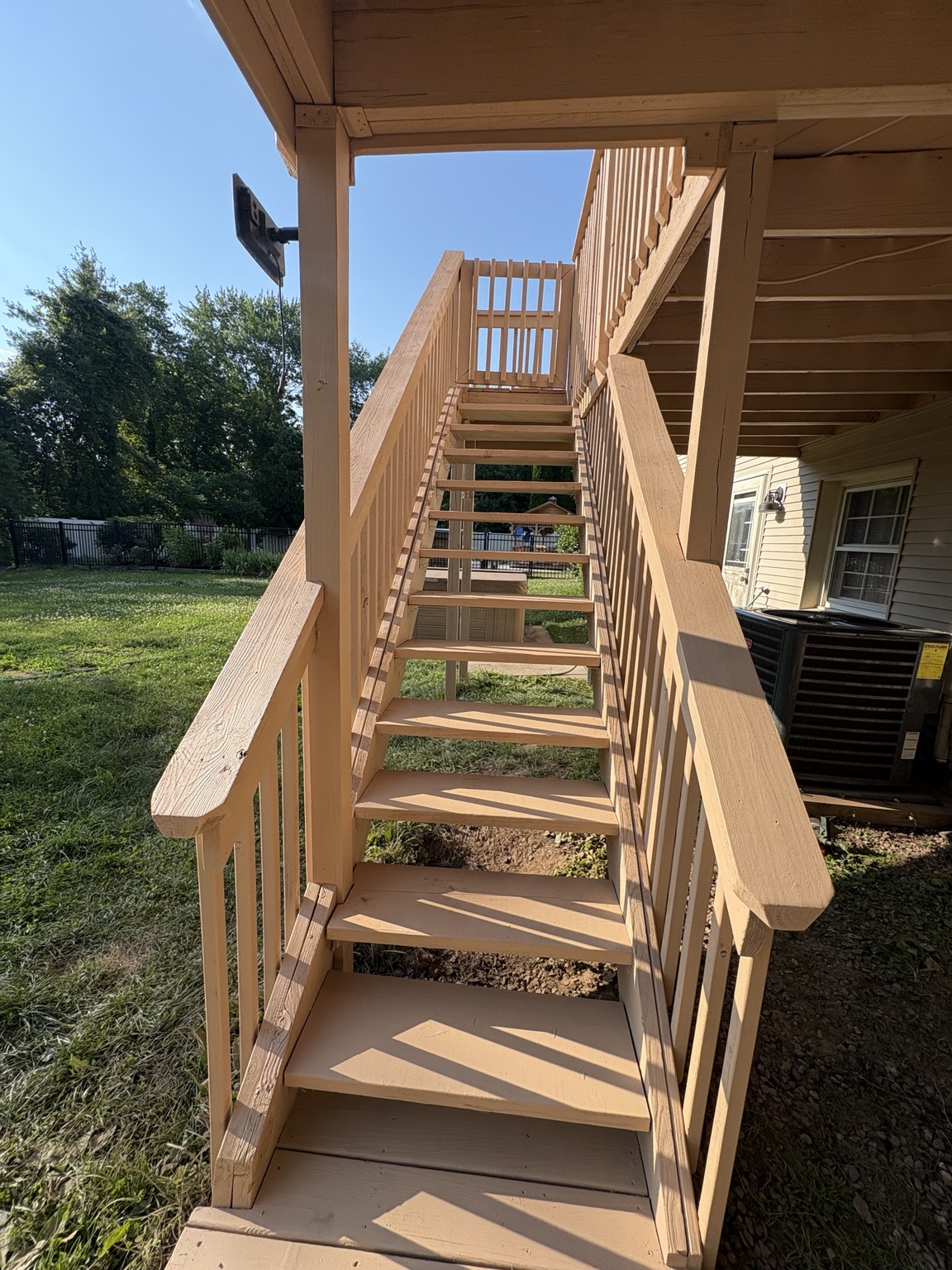 New pressure-treated wooden stairs attached to a raised deck