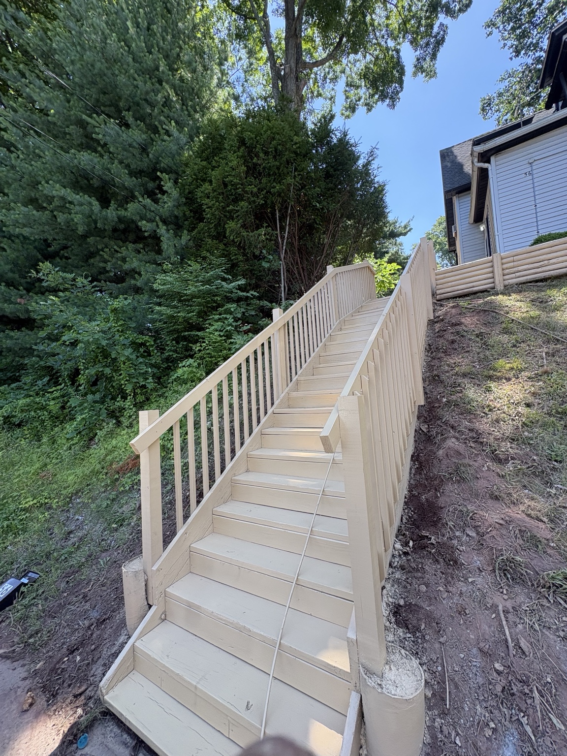 New wooden hillside stairs with railings viewed from below