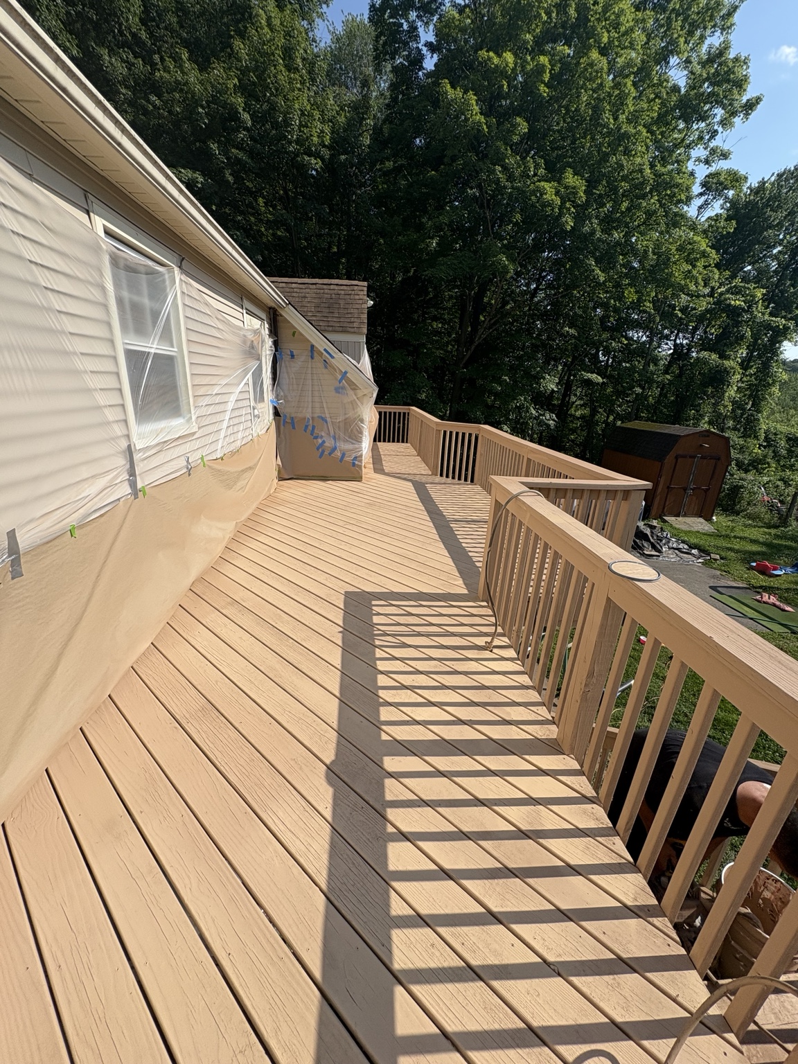 Finished wooden deck walkway and railing alongside a home